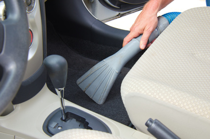 Closeup of a man vacuuming a car interior in the process of detailing an automobile