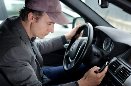 Man at wheel using cell mobile phone while driving car