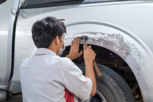 Man with hammer on fender of truck