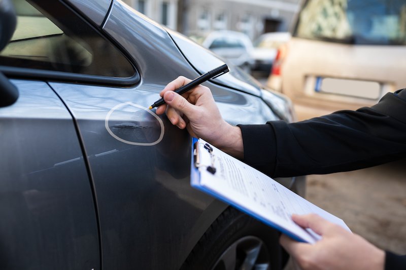 Insurance Agent Or Adjuster Inspecting Car After Accident