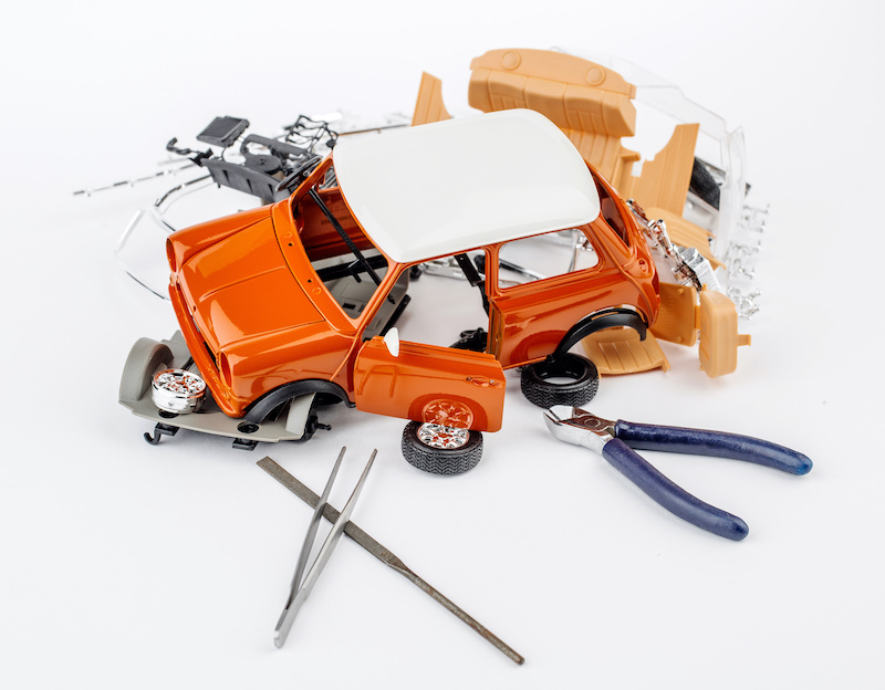 kit for assembling gray plastic car model on white background
