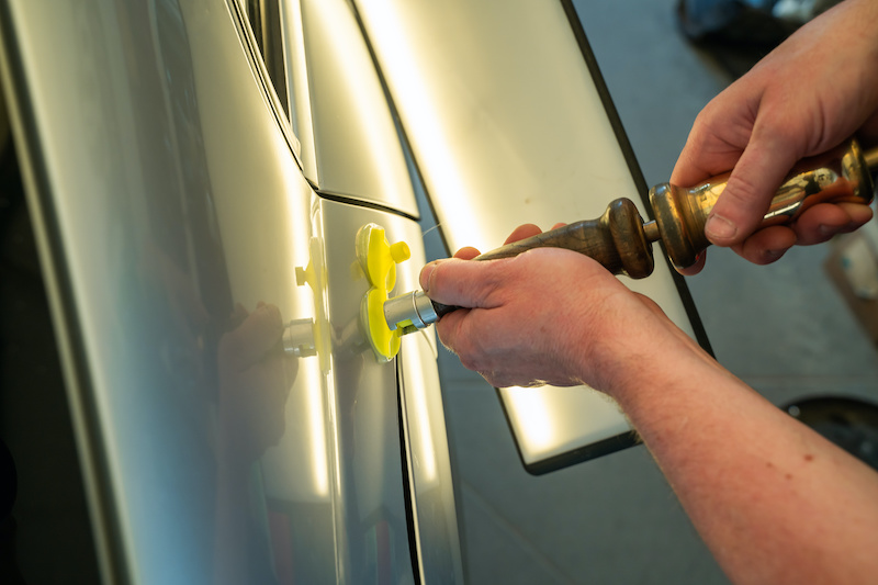 Process Of Paintless Dent Repair On Car Body. Technician s Hands With Puller Fixing Dent On Rear Car Fender. PDR Removal Course Training.