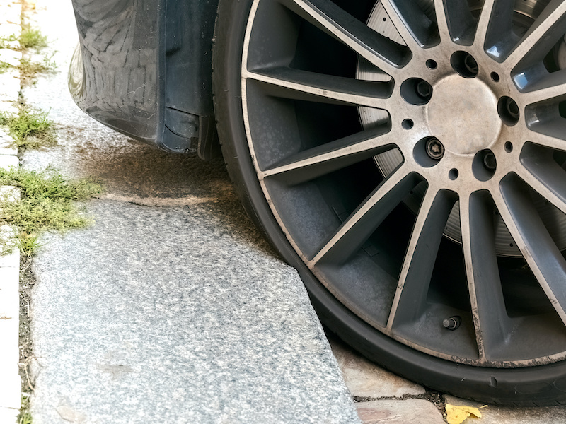 Poorly Parked Car on the Curb of a City Street with Sidewalk, Risk of Damage to the Low-profile Tire