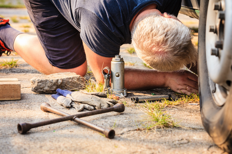 Casual man working under car fixing auto parts. Transportation, broken vehicles problems .