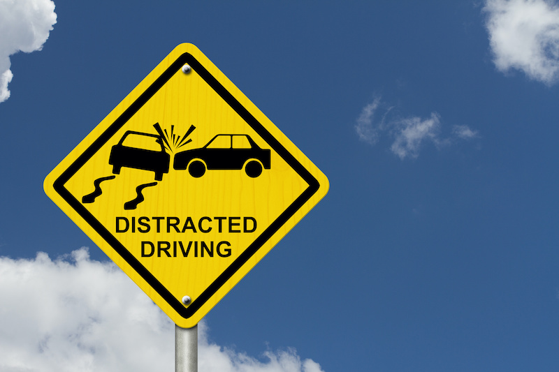 No Distracted Driving Sign, Yellow warning sign with words Distracted Driving and accident icon with sky background