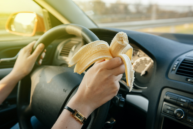 Woman eating a banana while driwing car on highway with 120 km/h