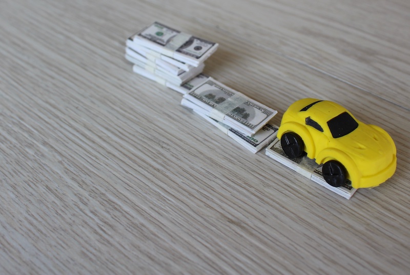 Selective focus image of toy car and stack of money. Car depreciation, value concept.