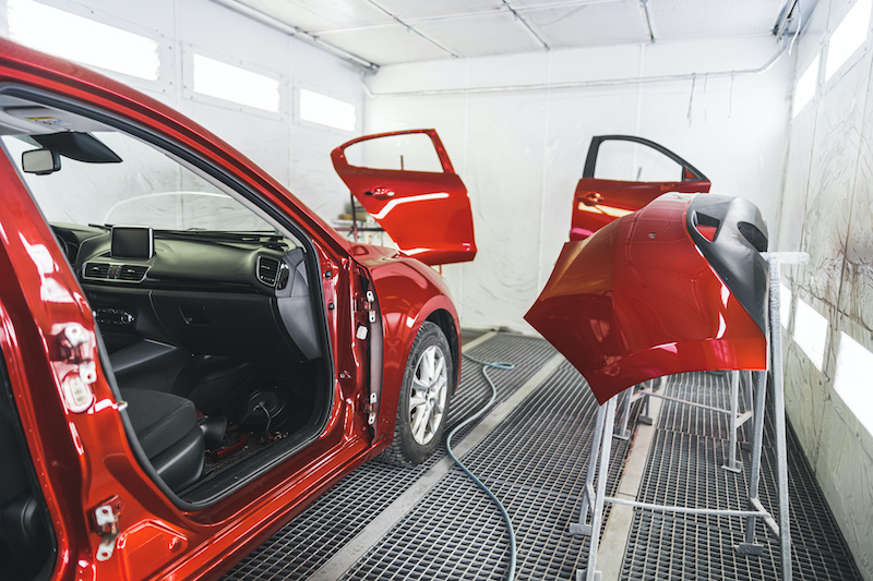 A luxury red car in a paint shop with its doors removed for a fresh coat of paint. High-quality photo