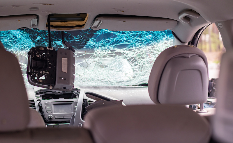 Damaged car window after an accident. Broken windshield as a result of an accident, inside view. Cabin interior details, view from the cab. Safe movement. Broken windshield. Glass crack and damage