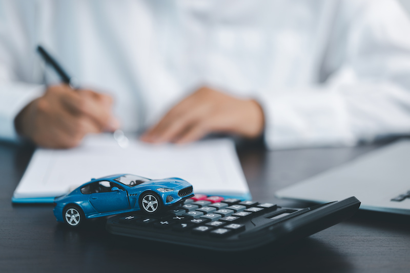 Blue Toy Car In Front Of Businessman Calculating Loan. Saving money for car concept, trade car for cash concept, finance concept.