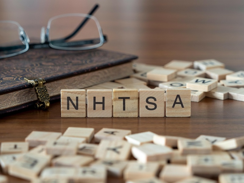 the acronym nhtsa for national highway traffic safety administration word or concept represented by wooden letter tiles on a wooden table with glasses and a book