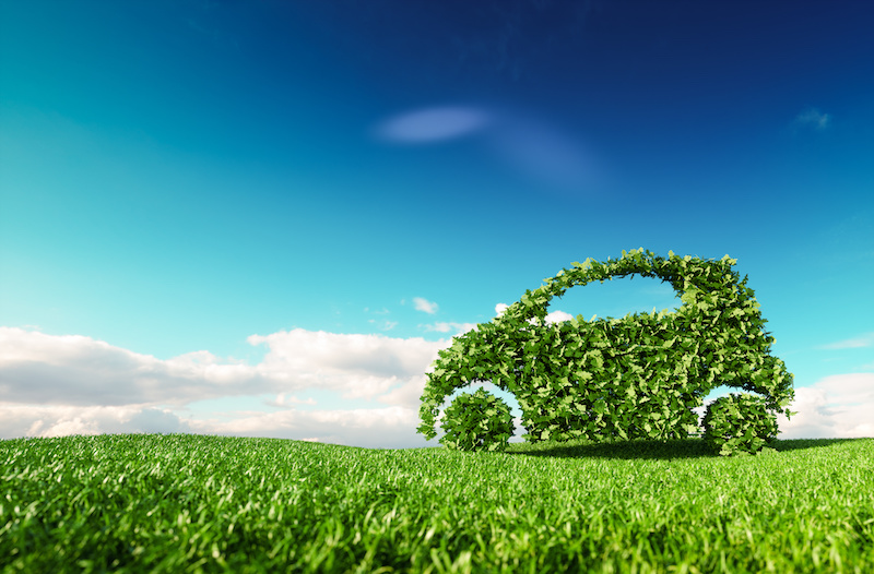 Eco friendly car development, clear ecology driving, no pollution and emmission transportation concept. 3d rendering of green car icon on fresh spring meadow with blue sky in background.