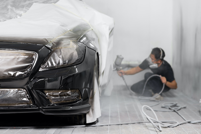 Auto body repair series: Black car being paint in paint booth