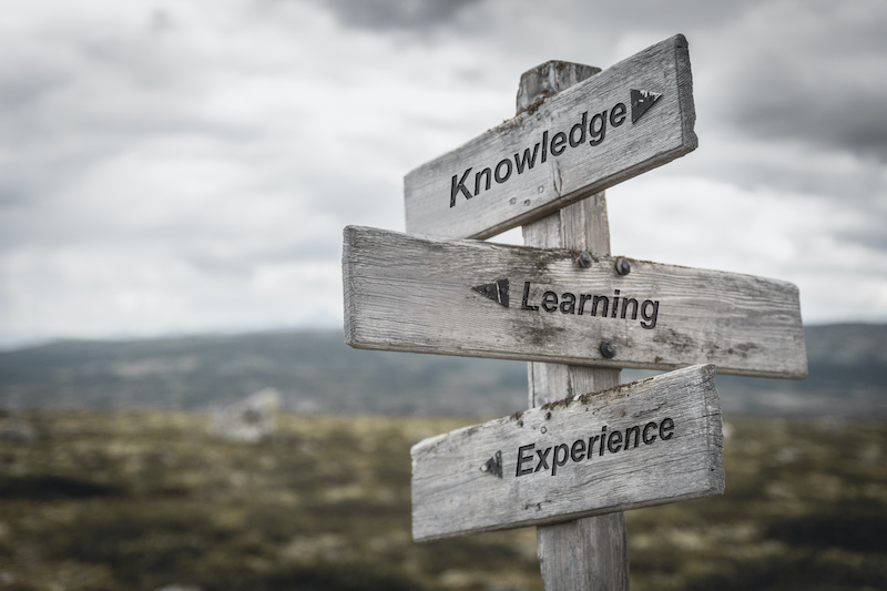 knowledge learning experience text on wooden sign outdoors.