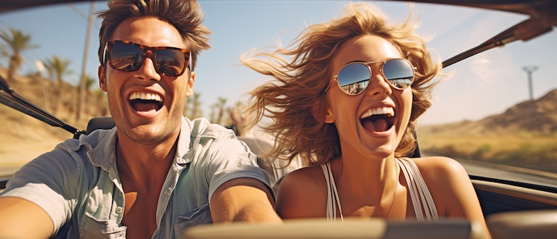 Fun summer road trip with a young couple driving a convertible automobile at a destination banner panorama vacation