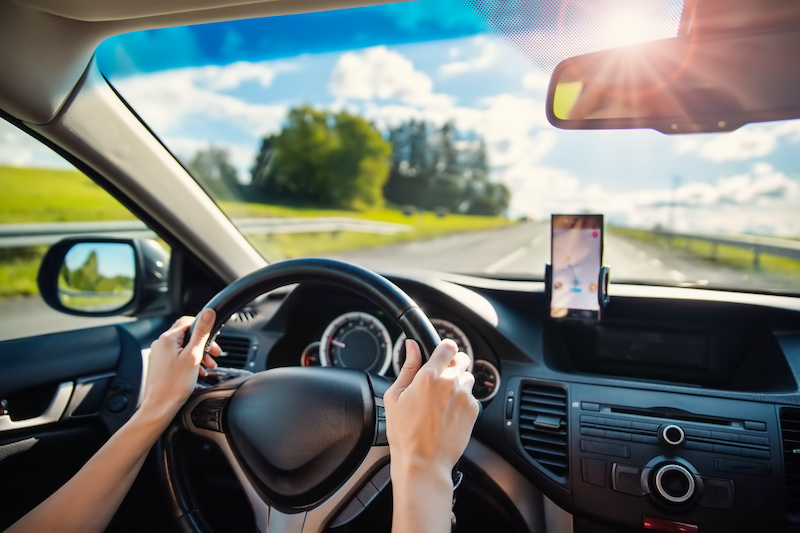 Woman driving a car and using a smrt phone as a navigator. Concept of vacation and travel.