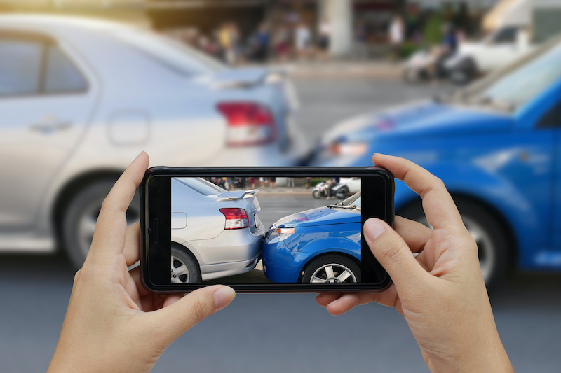 Close up hand holding smartphone and take photo at The scene of a car crash and accident, car accident for car insuranc claim.