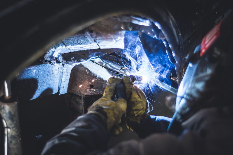 Mechanic welding on a car in an auto service repair shop in covina