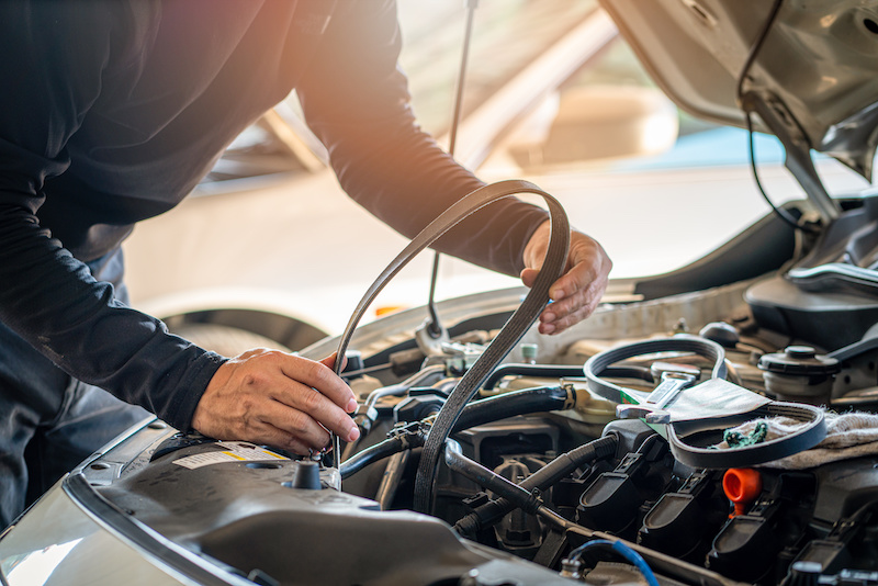 Professional mechanic man holding timing belt of a car for repair and preventive maintenance car in garage