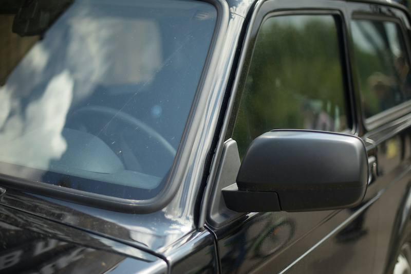 Black car in detail. Front rearview mirror. Car windshield. Machine Frame.