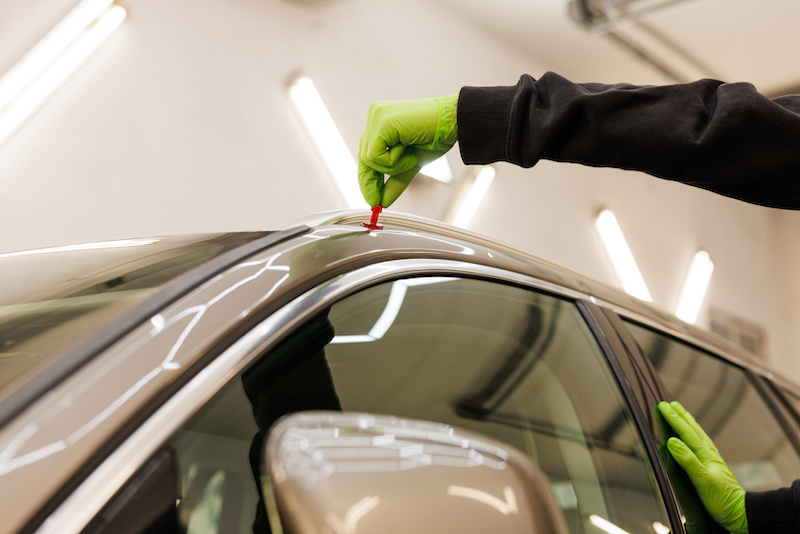 Person in green gloves repairing vehicle, working on car hood. High quality photo