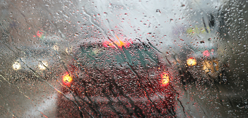 View from the car windscreen during rain and wet snow. Poor visibility while driving around the city. Snowy road.