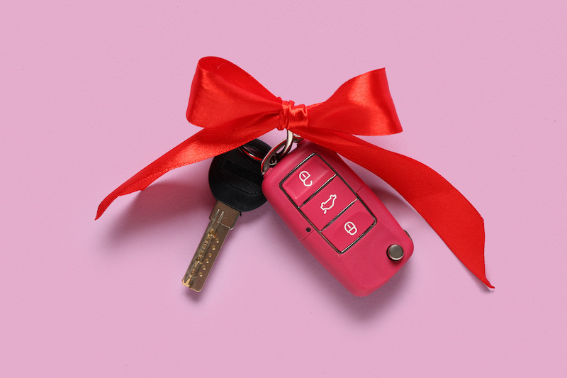 Gift keys of new car with bow on lilac background