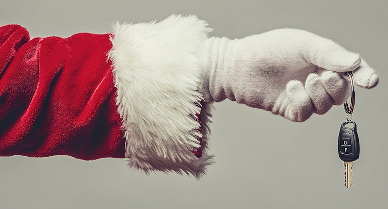 Santa's hand holding the keys to a new car on a light gray background. Space for copy. Christmas gift concept