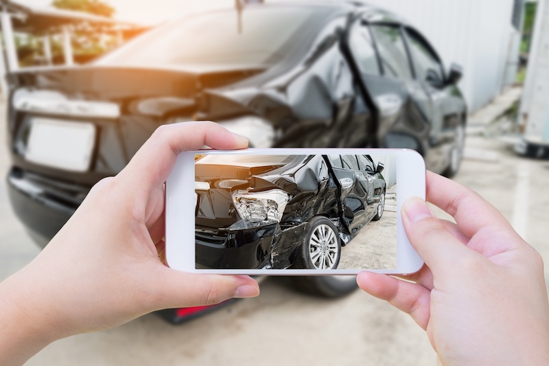 female hold mobile smartphone photographing car accident for insurance