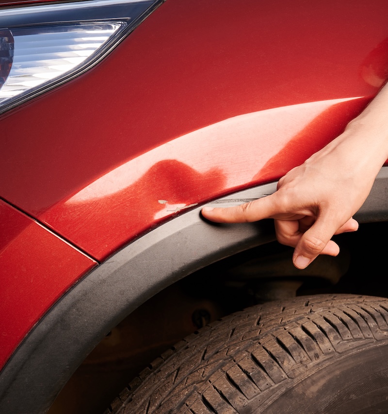Finger point at car scratch near wheel area