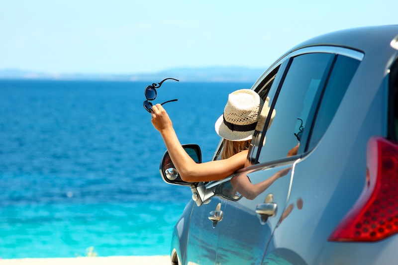 happy driver girl in hat with sunglasses  in car at sea in summer concept freedom and happy