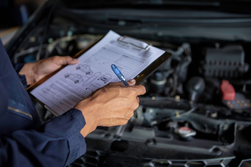 A mechanic service car in garage is check a list cars.