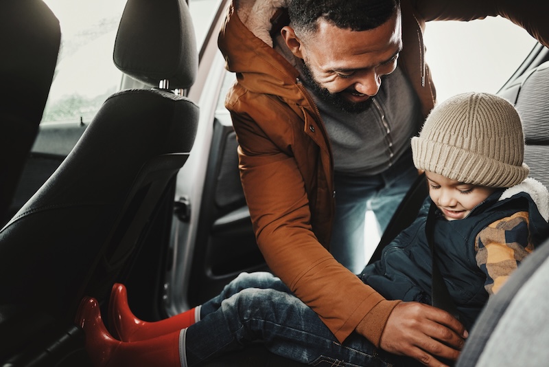 Father, help or child with seat belt for safety traveling on vacation, road trip or holiday in car together. Transportation, dad or happy parent with young kid or boy in vehicle for family weekend.
