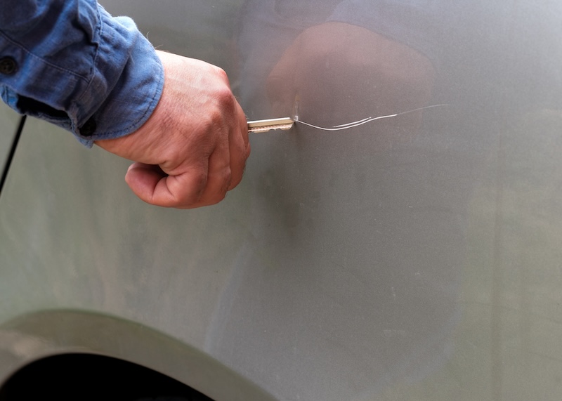 a man scratches a car with a keyl
