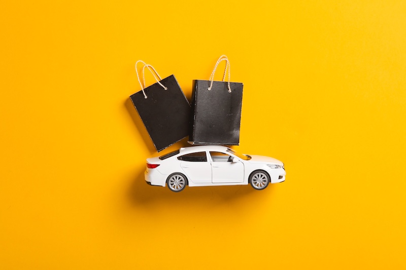 Toy car with Miniature black shopping bags on a yellow background. Black Friday, world shopping day, sale