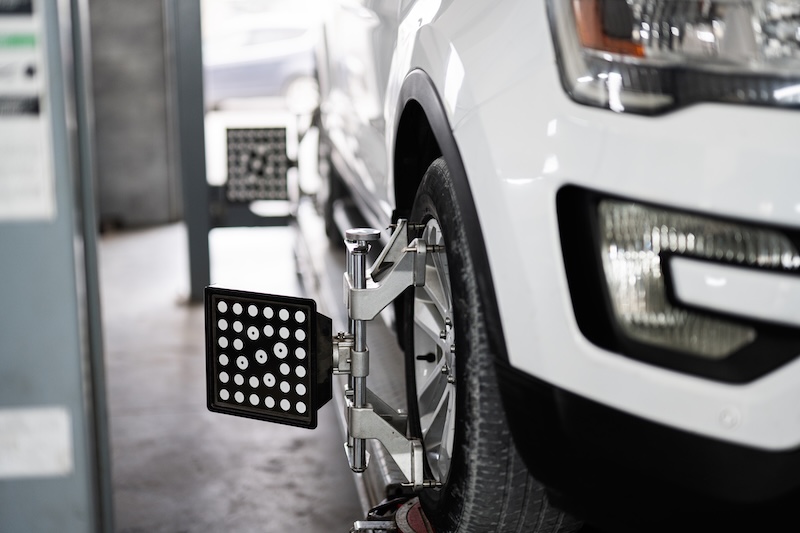 Detailed view of a vehicle undergoing wheel alignment in an automotive repair shop, showcasing precision equipment and technology for tire maintenance.