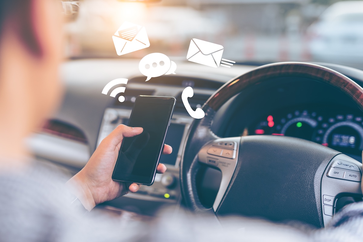 Man using smartphone while driving the car - transportation and vehicle concept with icon social media send email wifi chat read email