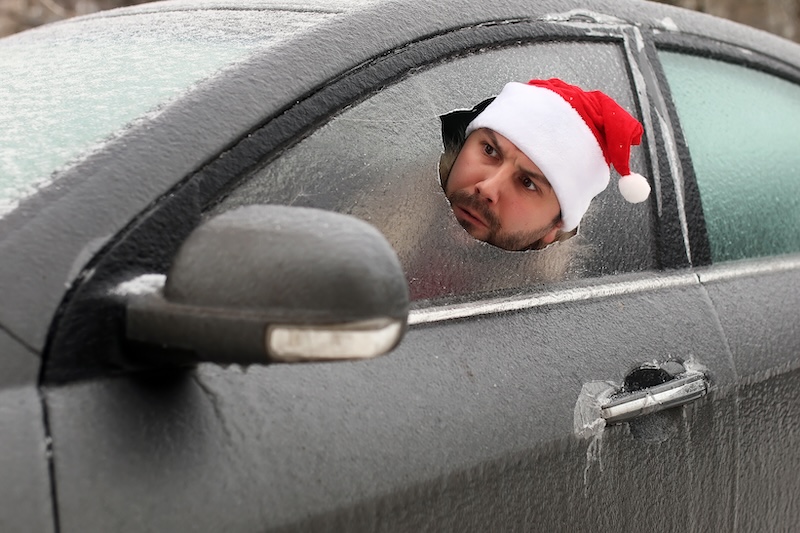 bearded man in a red cap of Santa Claus in a car with broken glass