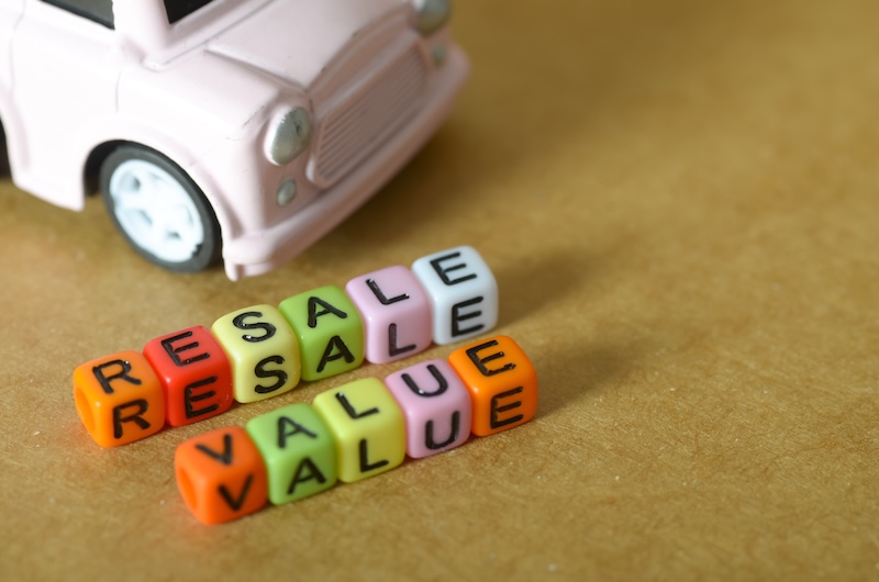 Resale Value Concept with Toy Car and Colorful Letter Beads on White Background
