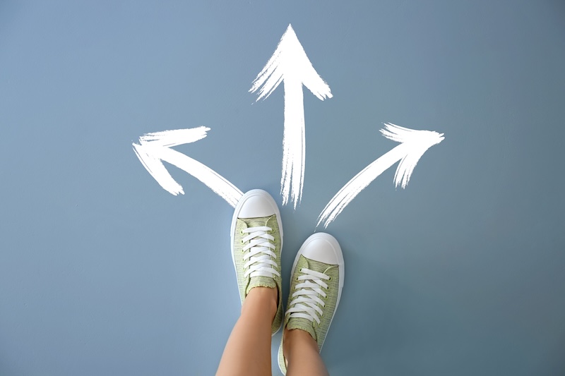 Woman standing on color background with arrows pointing in different directions. Concept of choice