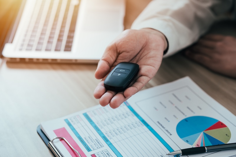 Car salesman selling service to buyer. Handing car keys. Car tax concept and money for credit, lease and lease.