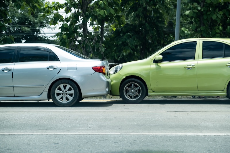 Automobile vehicle car accident on traffic road back and front colliding collision crashing into each other with minor damage to bumper and bonnet in city district hot stressful weather
