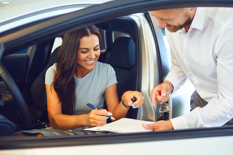 A young woman buys a car in a car showroom. A man signs a car rental agreement. insurance claim