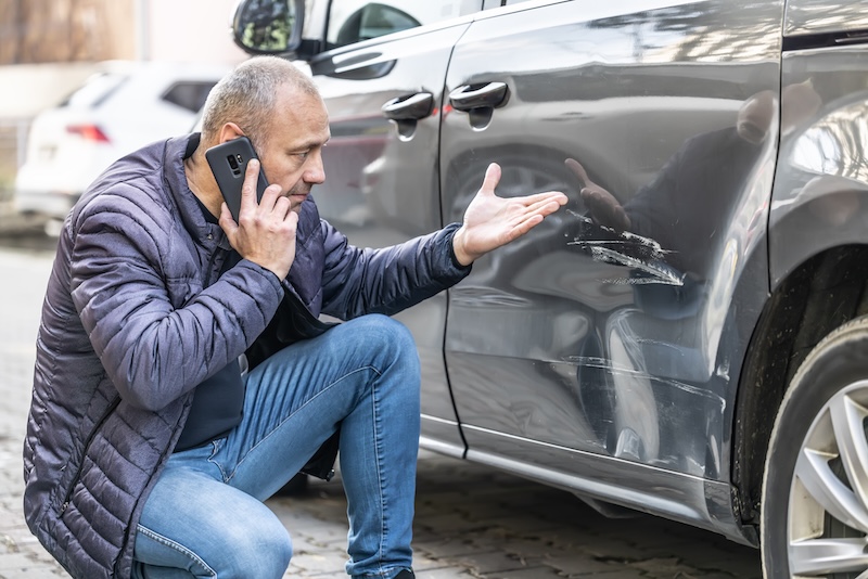 A man calls the insurance company because of the damaged door of his car because the culprit of the accident ran away from the parking lot.