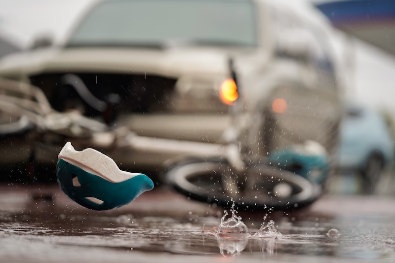 Blurred image of a traffic accident, helmet and bicycle after a car crashes into a cyclist on the road during heavy rain, spot focus.