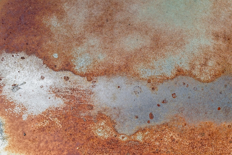 The abstract patterns of rust and corrosion on the side of an antique car