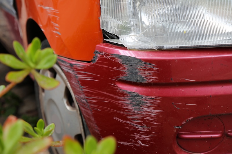 Car with scratched plastic bumper and damaged headlight. Minor accident result.