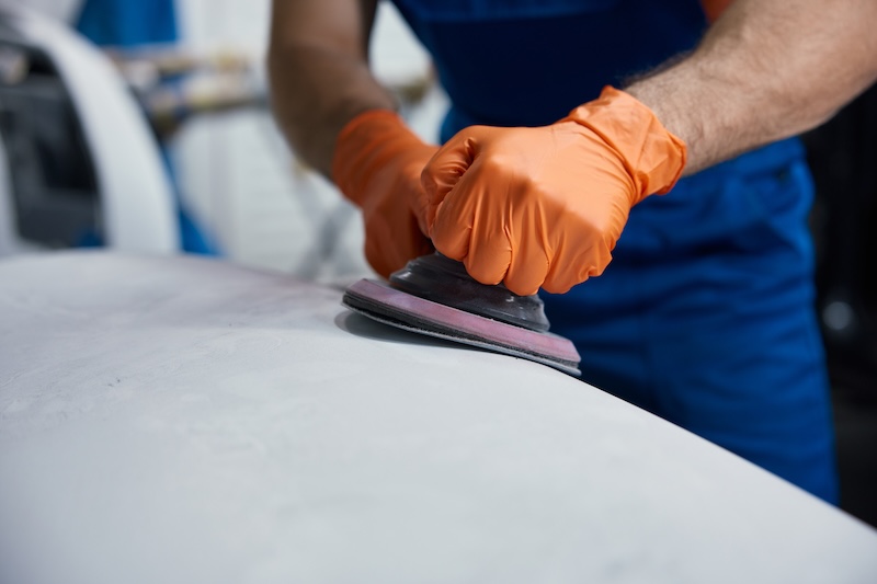Close-up of a worker sanding a car surface with an orbital sander, wearing orange protective gloves in a workshop. Work in the garage SSUCv3H4sIAAAAAAAACnRTTW/cIBC9V+p/WPkcVFiMsfMDeqvae9XDAOMsCjYrwGmjKP+9+CvLJpsb82bmzQdvXr5+ORwqBdHq6v7wMlvZts5NMQVI1o8ZpncbHnA0GErkKfCGlgDY0kJjkw8WXAkqSPo0woAZHCfnZvh1cVYxQZoixqIX7Z2fgvL/MsZ3Cp3b80OfzmJGCwINCR9yxSuKfbzfq33YHSsVpOyqfkF4jN9+Tsl4H6q7IiBOag74YaNG52BEP8Vq969lP+NEf3Z4i+w7DNbNTb7xrI8/b2t8wFE/X2aYU09TShjy4PqxHCa7GH0j2hlmDuMV3g4XormVYQLCEJNdvuYqI39yOUZ3bTImbzbgYHh+x8R7pWvVU8KVPJIaZE/aTjcE+ZEZJVFif83NddO0LSjSS61JrXNq2zRIOsayB480k12Kr4/XQhEBHcIqqa2PirU9qp5TclSApKZUkJYpReRRMEBV1xzbhXKdpXr8m/c+LIraSGEy1hcKe/IaXHynRbBnCHCVdw5W2/GhQHw6LRd1kfs0pjBvrdrXUDnvz6Cyku4PfS6DO36CGHO42fHyDpYDKeqMPi072Fgrkw9lNhmvmeCUCyGlqBsqui1gPcWTzTxLO3uD09l5MDgXvWjz6h6ZlLSlnezE9ht7v1n8g80afpdbHPiWypm8qOgj97HrhPz404vUrSn3bedSVc9N1k3TEFP3htQdsqweACJqoFQ3nRIc8n+//gcAAP//AwDRnQ6IDQUAAA==