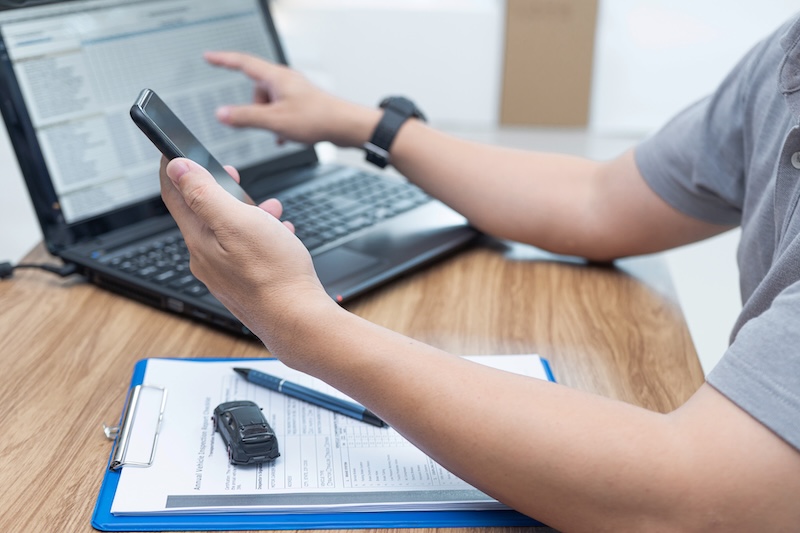 Service staff use smartphone Check details about car repairs compared to the data in laptop to estimate the cost of car repairs in office car service center