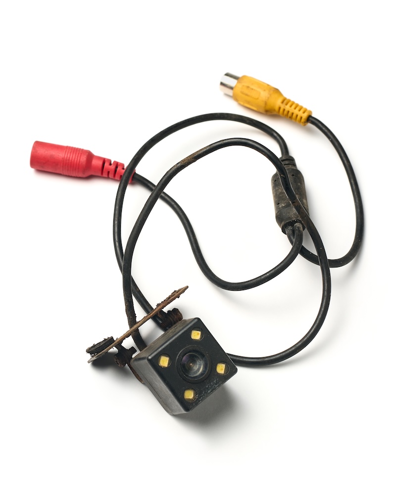 old used car backup camera with cables isolated white background, dirty plastic metal housing with rca connectors, top view